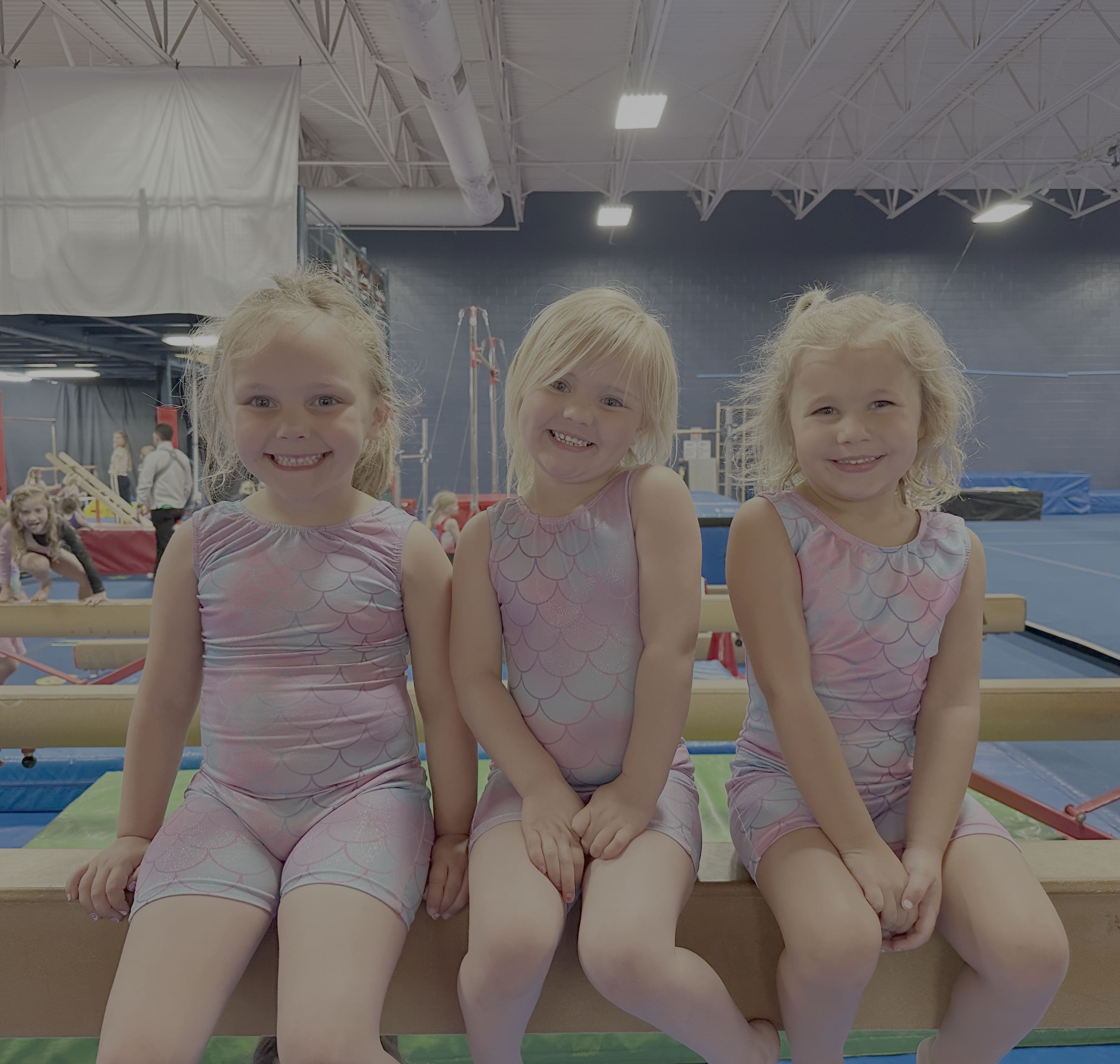 matching girls sitting on a beam